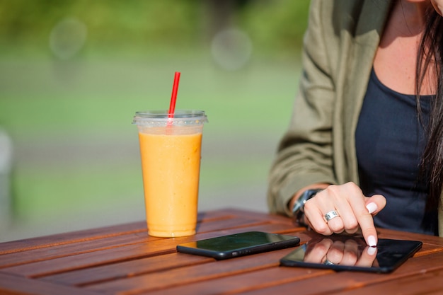 Batido de mango en un vaso en mano femenina de cerca