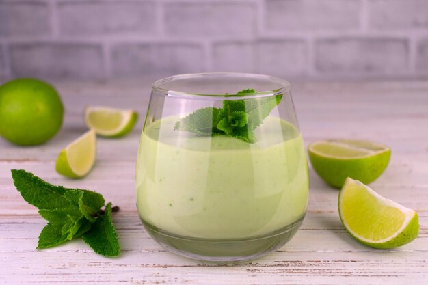 Batido de menta y lima en un vaso sobre un fondo blanco de madera