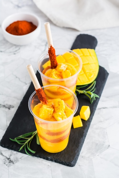 Batido mexicano de mangonada de mango con salsa chamoy y paja de tamarindo en vasos de plástico Vertical