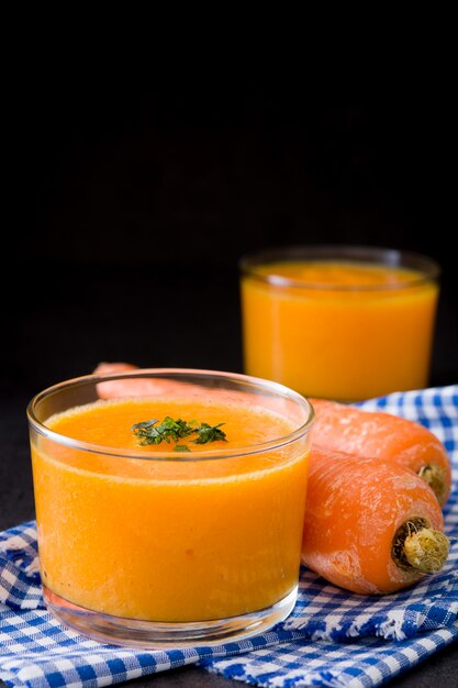 Batido de naranja, manzana y zanahoria sobre superficie negra