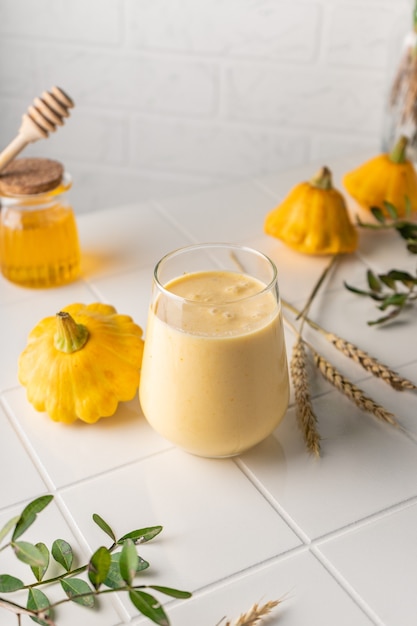 Un batido natural elaborado con calabaza amarilla. bebida de otoño con miel y leche. sobre un fondo claro, posición vertical