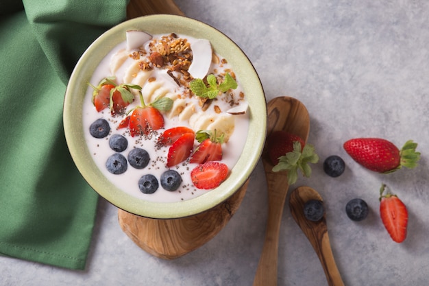 Batido ou tigela batida com granola, frutas e sementes. Bebida probiótica orgânica ou iogurte com morango, sobre fundo cinzento branco. Saúde intestinal. Bebida láctea fermentada. Comida da moda.