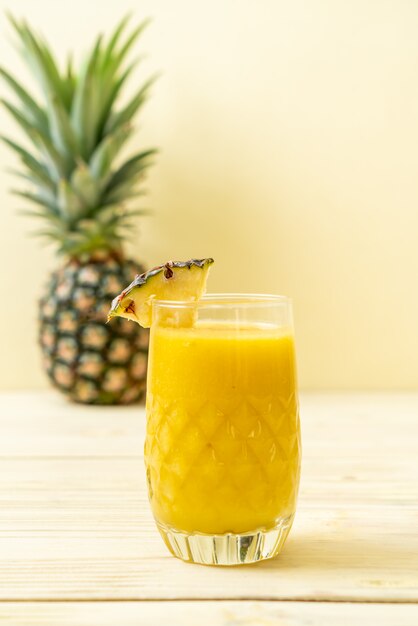 Foto batido de piña fresca de vidrio en la mesa de madera