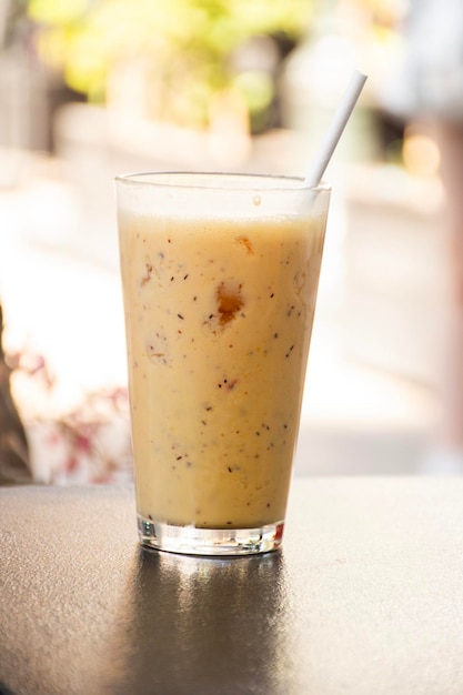 Batido de piña naranja con refrescante hielo picado en un día caluroso en la ciudad con un cuadrado borroso al fondo