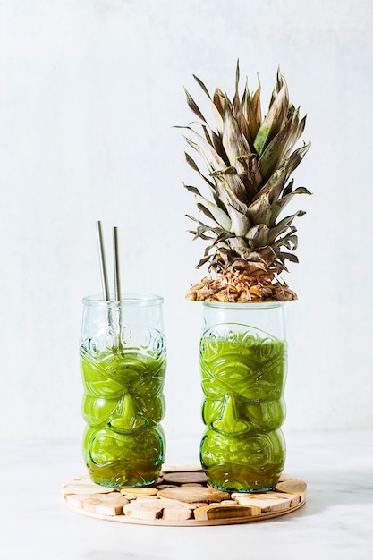 Batido de piña verde recién preparado en vasos con caras. Concepto de desayuno saludable por la mañana.