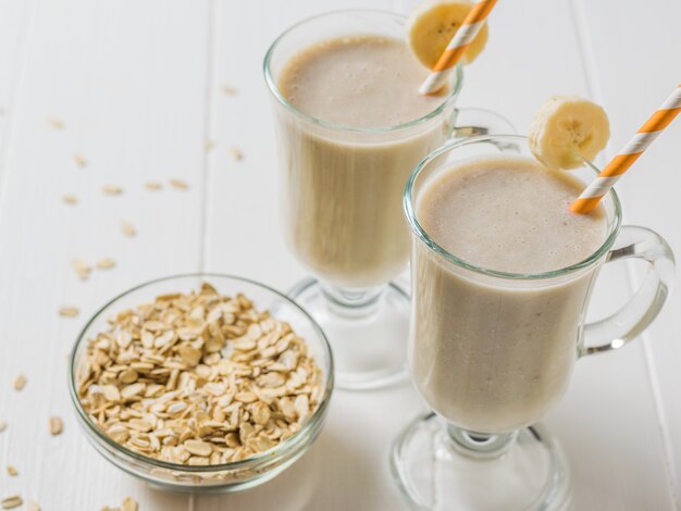 Foto batido de plátano con avena en vasos sobre una mesa blanca