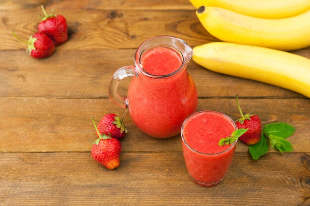 Batido de plátano fresa fresca con menta sobre un fondo de madera rústica. Comida saludable