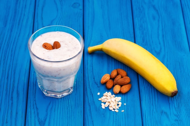 Batido de plátano y leche de almendras en un vaso, pared azul