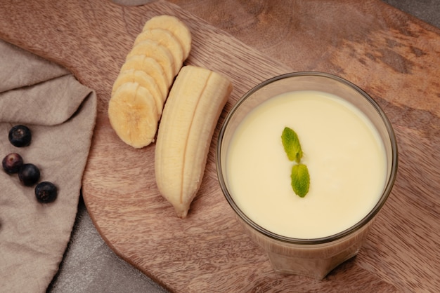 Batido de plátano con menta sobre tabla de cortar de madera y paño de cocina de lino