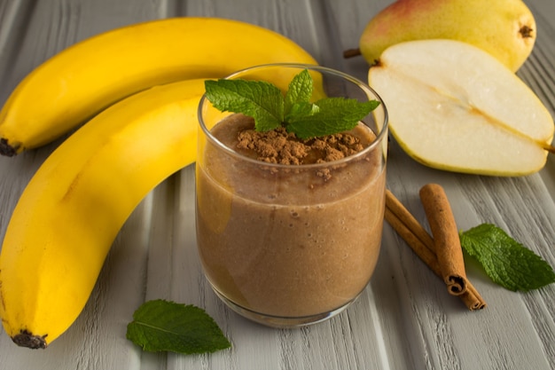 Batido de plátano, peras y cacao en el fondo de madera gris