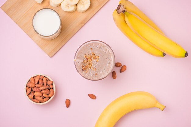 Batido de plátano recién hecho en un vaso sobre fondo rosa