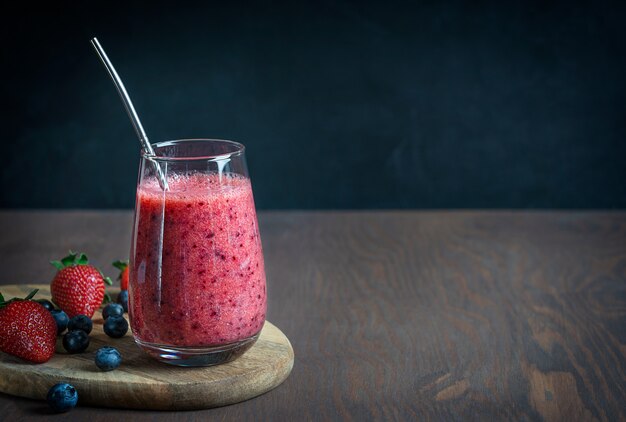 Batido refrescante de jugosas fresas y arándanos servido en vaso con pajita de metal