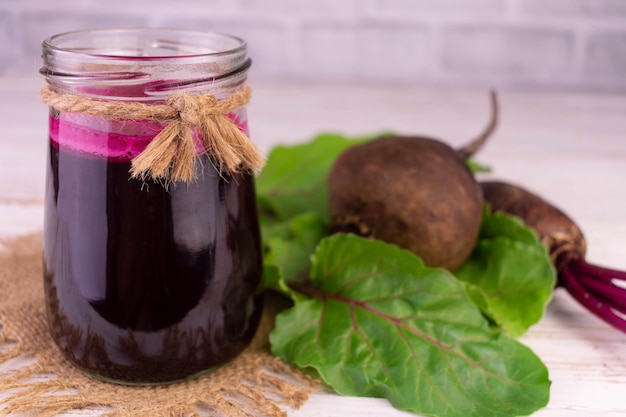 Batido de remolacha saludable en un frasco sobre un fondo de madera blanca.