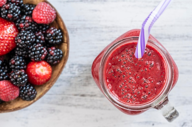 Batido rojo orgánico fresco en una taza de vidrio sobre una mesa blanca vista superior de primer plano Refrescante bebida de frutas de verano Batido de frambuesa y fresa