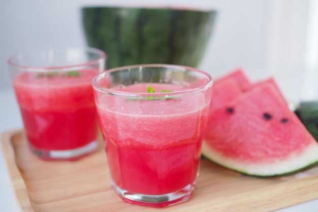 Batido rojo de sandía en un vaso y melón cortado en trozos, colocado sobre la mesa dando una sensación fresca, dulce y fresca.