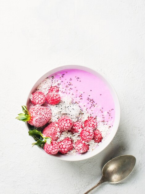 Batido rosa en tazón con pitaya, fresa y frambuesa