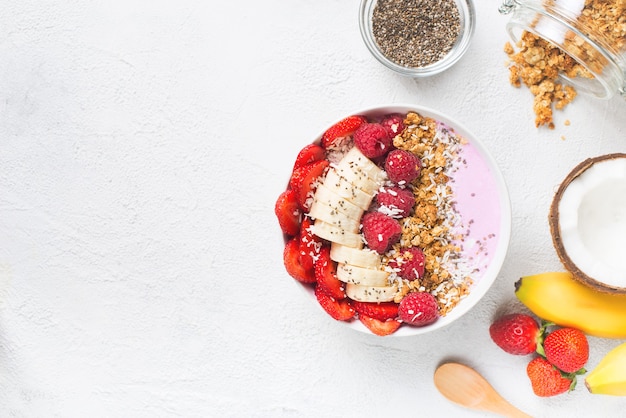 Batido rosa en un tazón con plátano, fresa y frambuesa