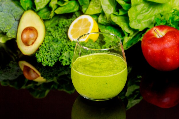 Foto batido saludable de verduras en vidrio en mesa negra.