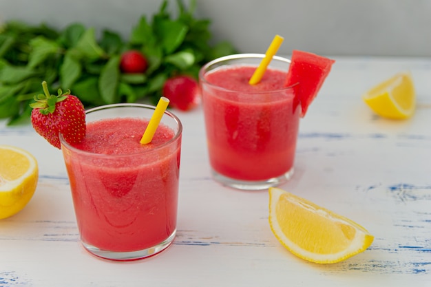 Batido de sandía fría con menta, limón y fresas en vasos. Coloridas bebidas refrescantes para el verano