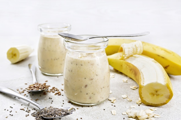 Batido con semillas de chía, semillas de lino, avena, arroz inflado y plátano en dos frascos de vidrio sobre un fondo de mesa de granito