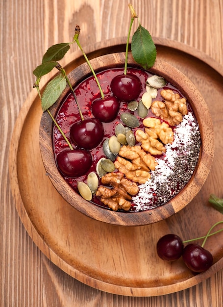 Batido de tazón con semillas de chía de cereza, semillas de calabaza y nueces en una vista superior de fondo rústico