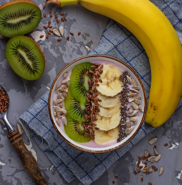 Batido en un tazón con semillas de plátano, kiwi, chía, lino y girasol