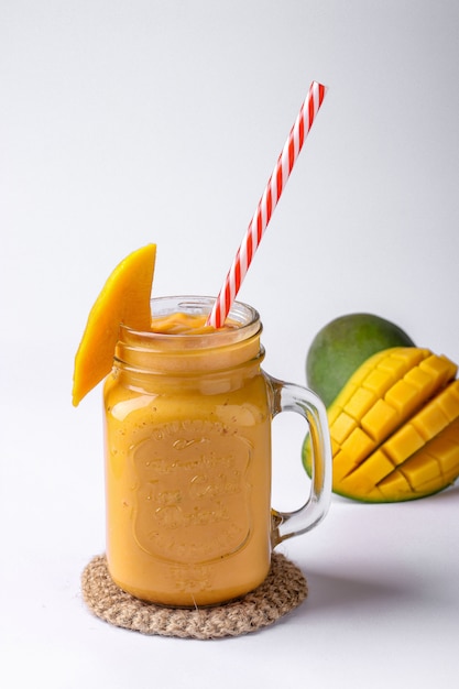 Foto batido tropical de mango sobre una superficie blanca, orientación vertical