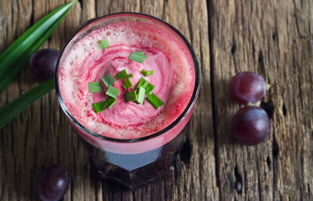 Batido de uva saludable y hierba en el fondo de la mesa de madera