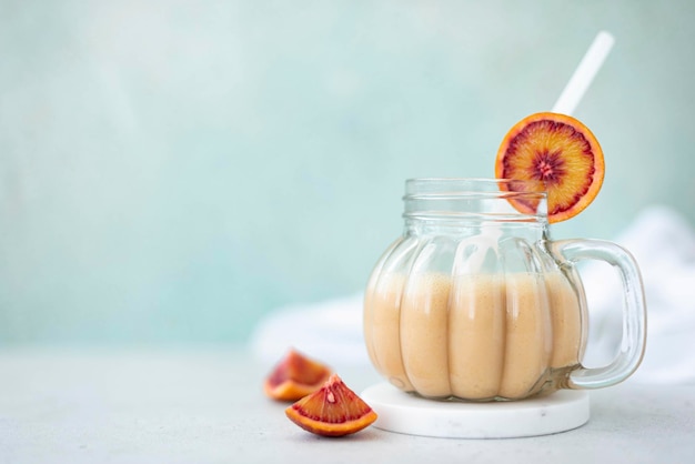 Batido de vainilla con naranjas rojas en una taza de vidrio