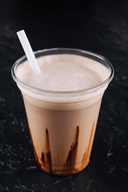 Batido en un vaso de plástico sobre fondo negro