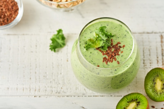 Batido verde detox con col rizada, espinacas y kiwi sobre una pizarra gris claro