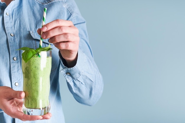 Batido verde de espinacas Batido vegano de semillas de chía de albahaca verde de espinacas y menta en vidrio en manos de mujer sobre fondo azul Comer limpio dieta alcalina pérdida de peso concepto de alimentos Mock up