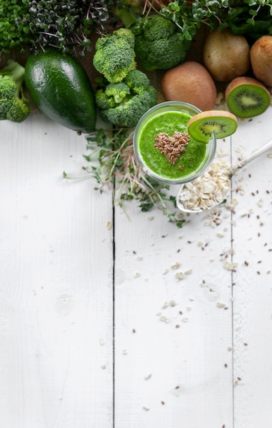 Batido verde fresco y sabroso con ingredientes sobre superficie de madera