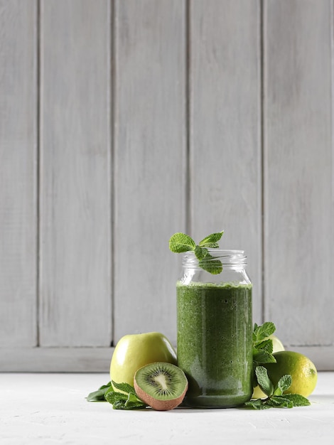 Un batido verde con una hoja de menta al lado.