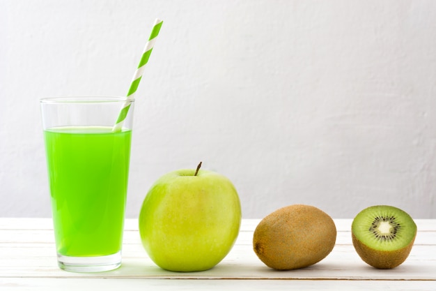 Batido verde con manzana y kiwi sobre una mesa de madera blanca