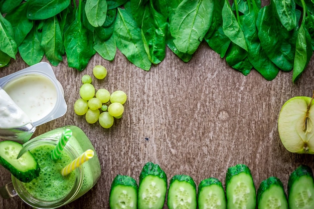 Batido verde con manzanas, yogur, espinacas, pepino sobre fondo de madera. Lay Flat con lugar para el texto. Concepto de comida vegana y saludable.