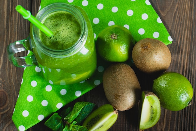 Batido verde mezclado con ingredientes en la mesa de madera