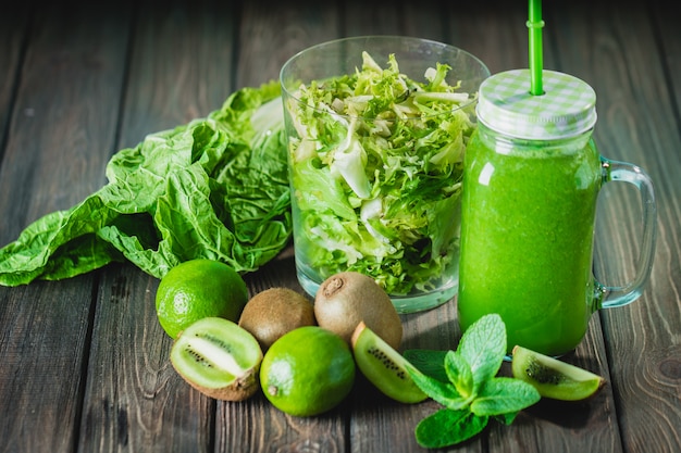 Batido verde mezclado con ingredientes en la mesa de madera