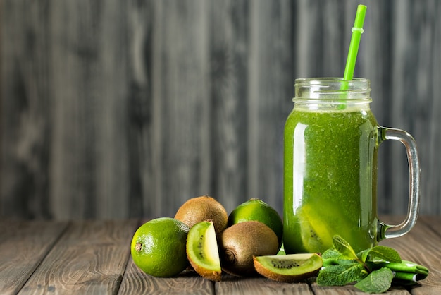 Batido verde mezclado con ingredientes en la mesa de madera