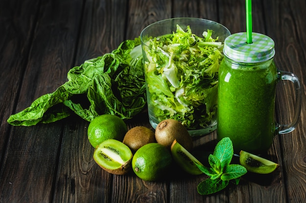 Batido verde mezclado con ingredientes en la mesa de madera