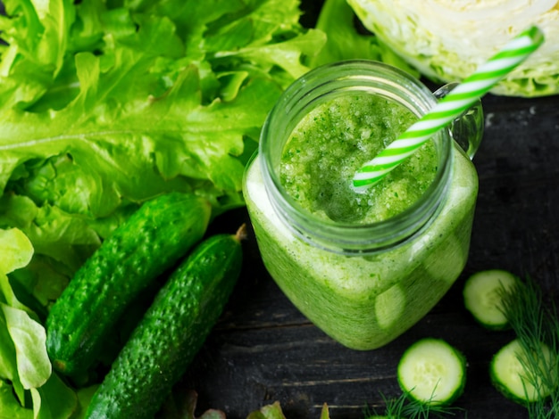 Batido verde con pepino, repollo y verduras saludables en la mesa