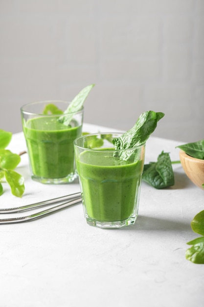 Batido verde saludable con espinacas aguacate plátano y leche vegana en dos vasos y fresco