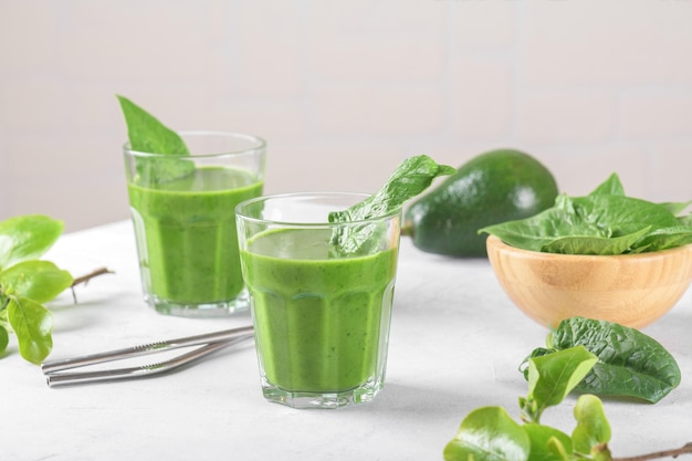 Batido verde saludable con espinacas aguacate plátano y leche vegana en dos vasos y fresco