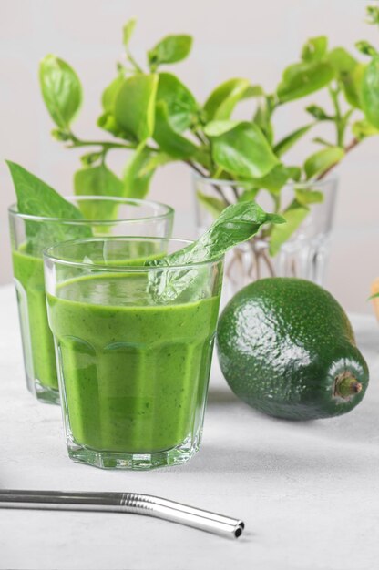 Batido verde saludable con espinacas aguacate plátano y leche vegana en dos vasos y fresco