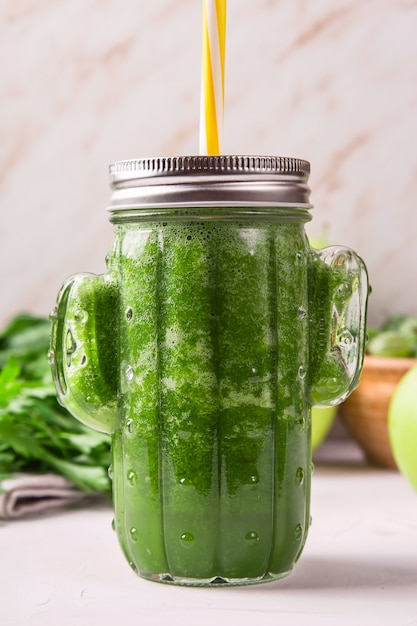 Batido verde en un vaso con forma de cactus entre los ingredientes verdes