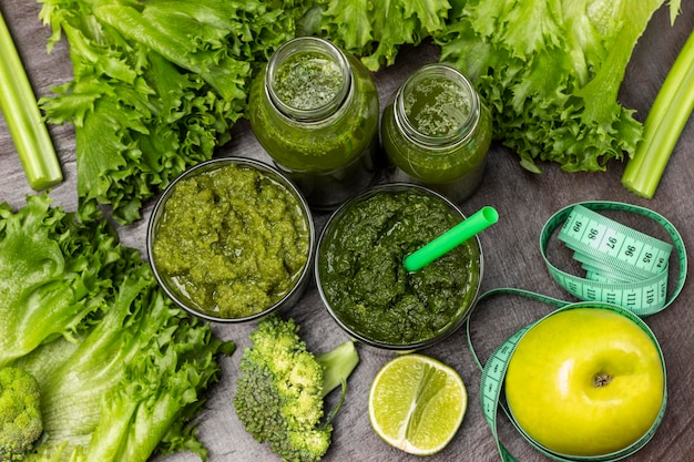 Batido verde en vasos y botellas Cinta métrica alrededor de una manzana