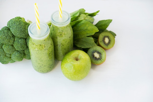 Batido verde vegetariano con verduras y frutas en botellas de vidrio, espacio de copia