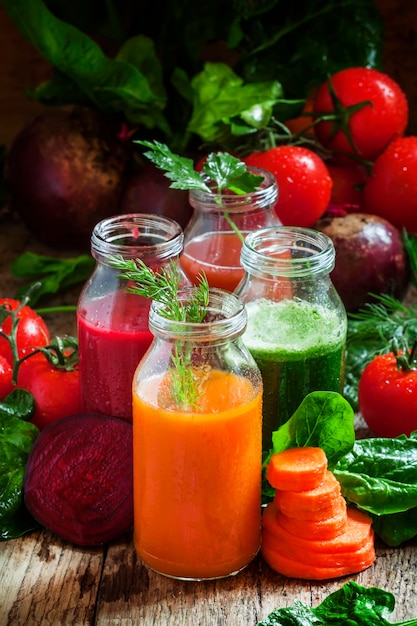 Batido de verduras en botellas pequeñas enfoque selectivo de fondo de madera oscura.