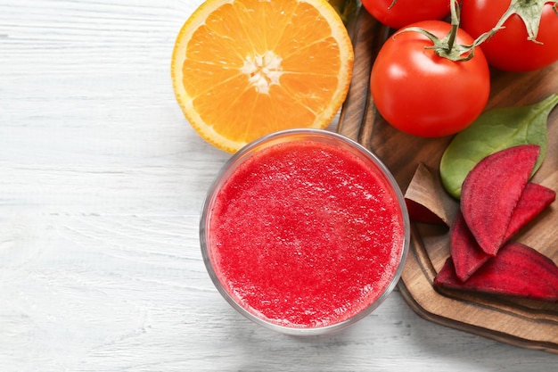 Batido de verduras frescas y rodaja de naranja en la mesa