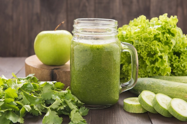 Batido de verduras y frutas verdes saludables en la mesa de madera rústica